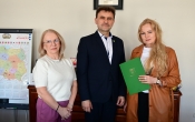 trzy stojace osoby, mezczyzna w srodku po bokach kobiety