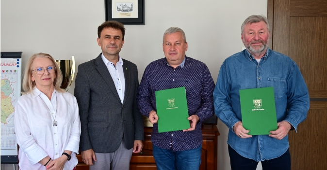 grupa osob, 1 kobieta i 3 mezczyzn, 2 trzyma zielone teczki